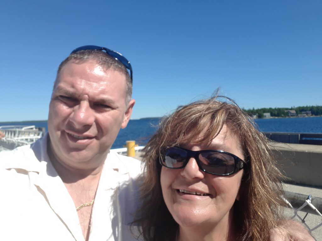 My wife, Ivana, and I wait for the ferry at Tobermory, Ontario.  Blue sky and water background.