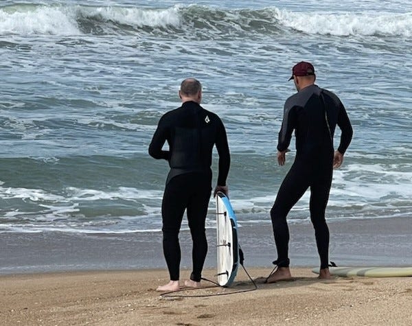 2 men stand by the water with surfboards. Me and my instructor. Ocean in background.