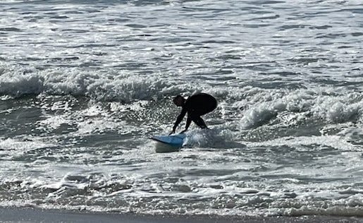 A man rides a surf board, about to topple off.