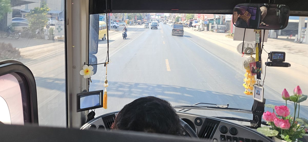 from the front row of a tour bus. Passing a slow motorcycle with a trailer, facing oncoming traffic.