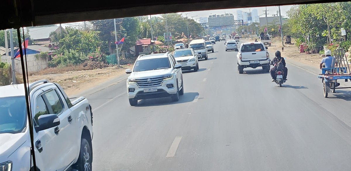 Phnom Penh in the distance, a busy 2 lane road filled with traffic.