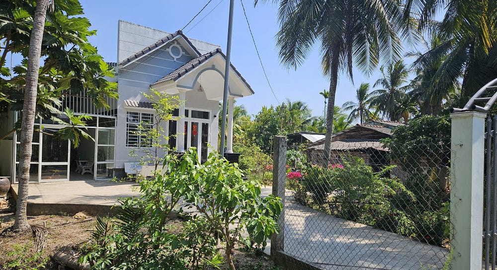 A new, tall white house sits beside a ramshackle shack.