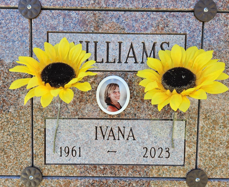 A marble columbarium spot with a cameo picture and carved name “Williams” “Ivana 1961–2023” A sunflower on either side of the cameo