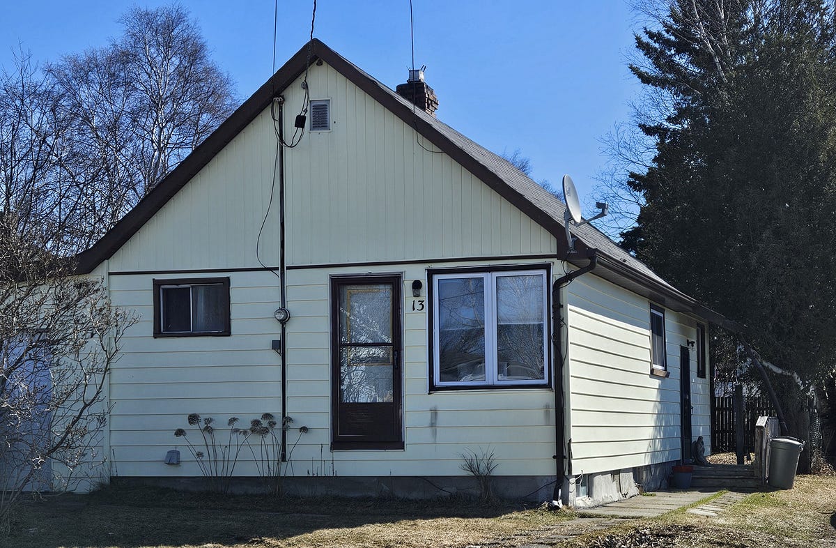 A small bungalow. yellow with brown trim and a white garage