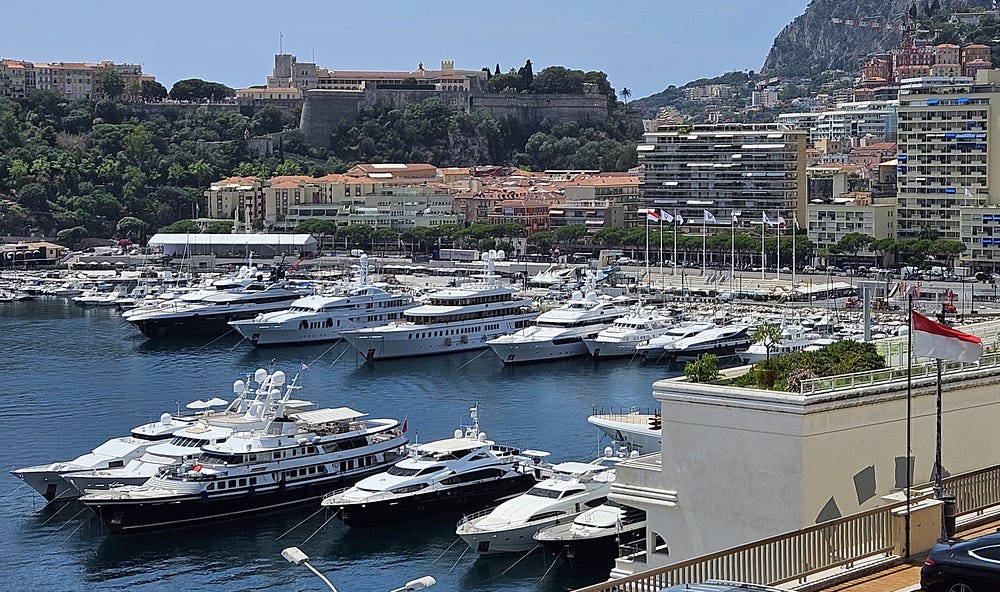 Monaco harbour. Many large yachts are moored in the water with condos in the background.