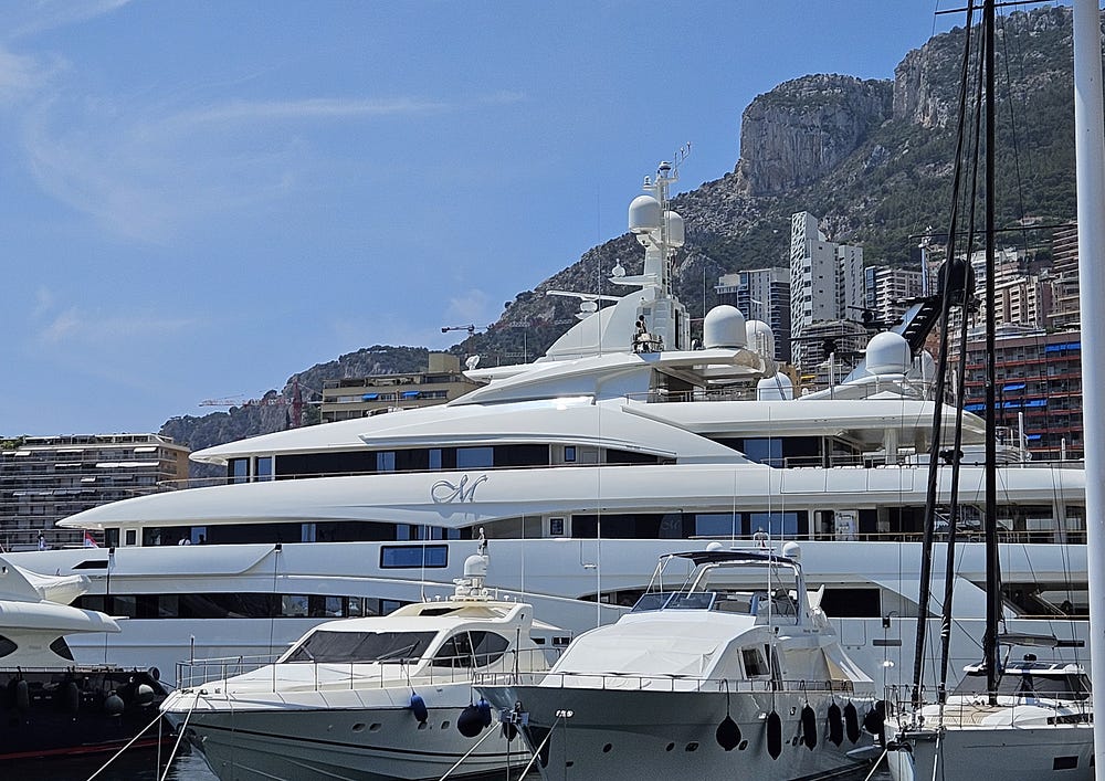 A huge white yacht dwarfs smaller yachts in the Monaco harbour