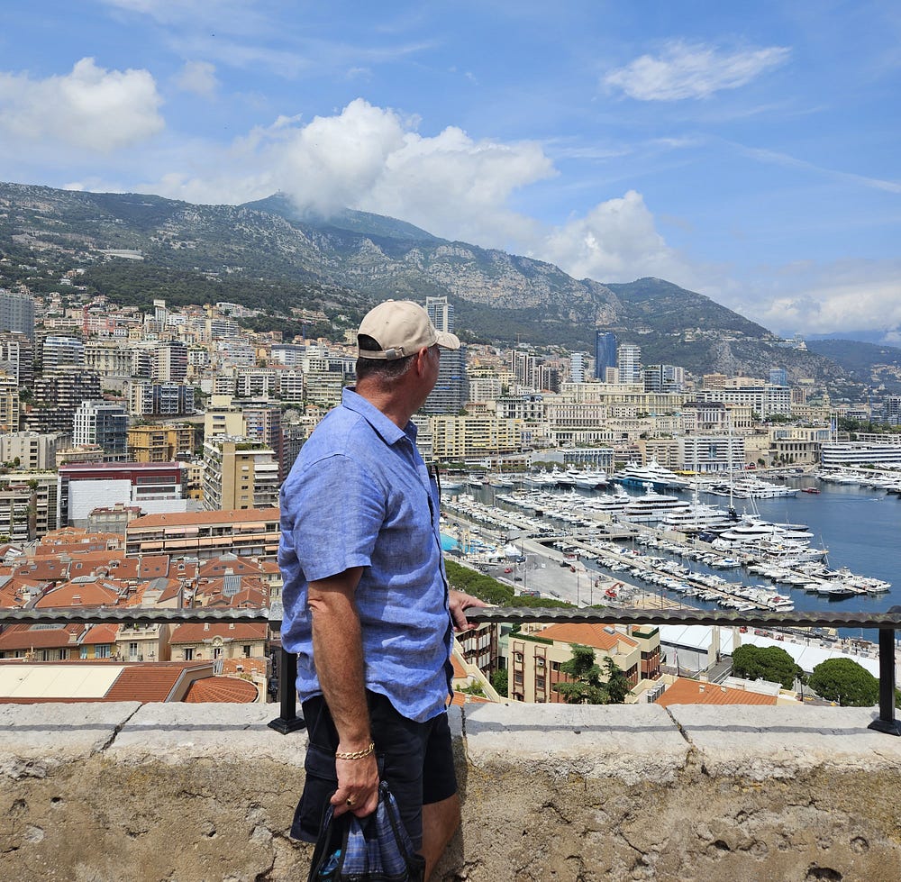 A man in a blue shirt overlooks the Monaco harbor from a distance