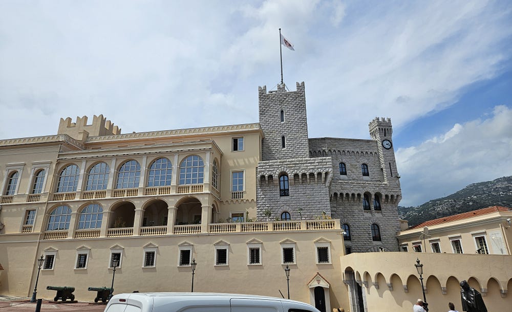 Stone fortifications at the front of a building, brick palace behind. Monaco.