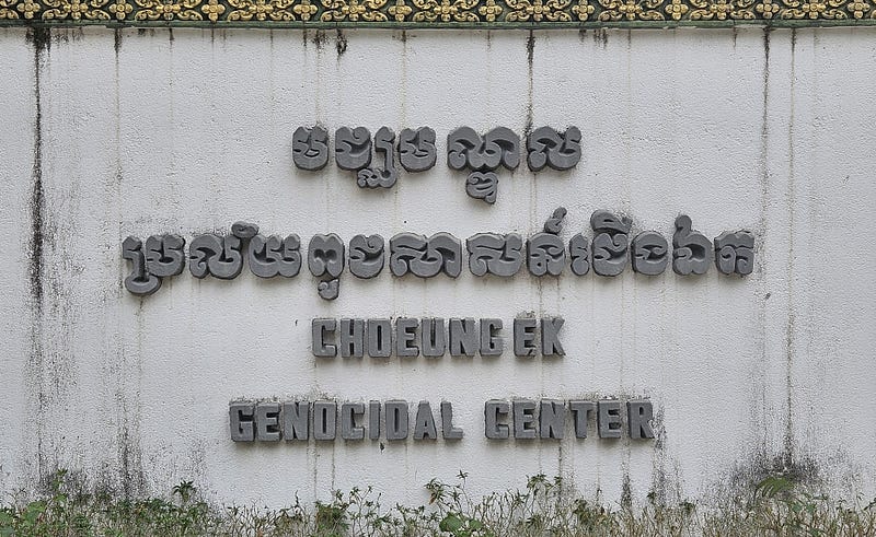 A concrete sign at the entrance to the memorial. Writing in Khmer and English