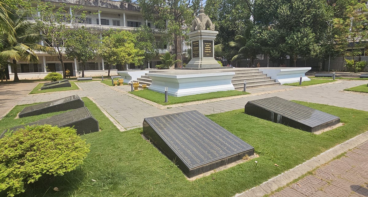 A memorial. Names are written on large black granite plaques that surround a 12 foot tall memorial to the victims of Pol Pot.