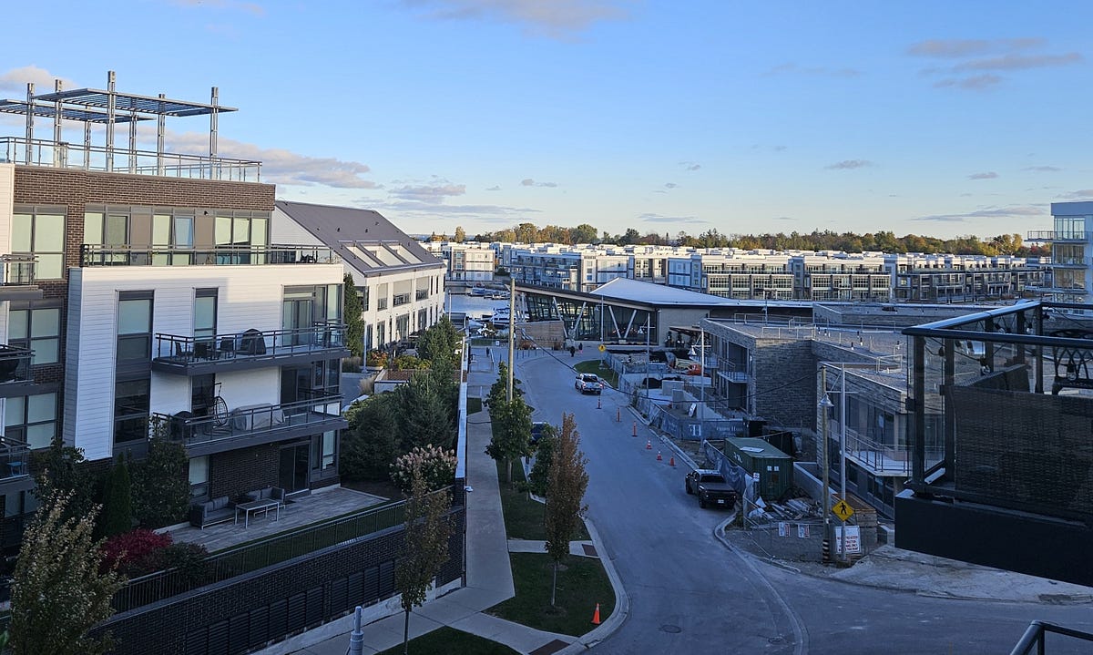 the view from my 4th-story balcony. A road with condos on both sides. Boats in the marina behind the large lake club community building